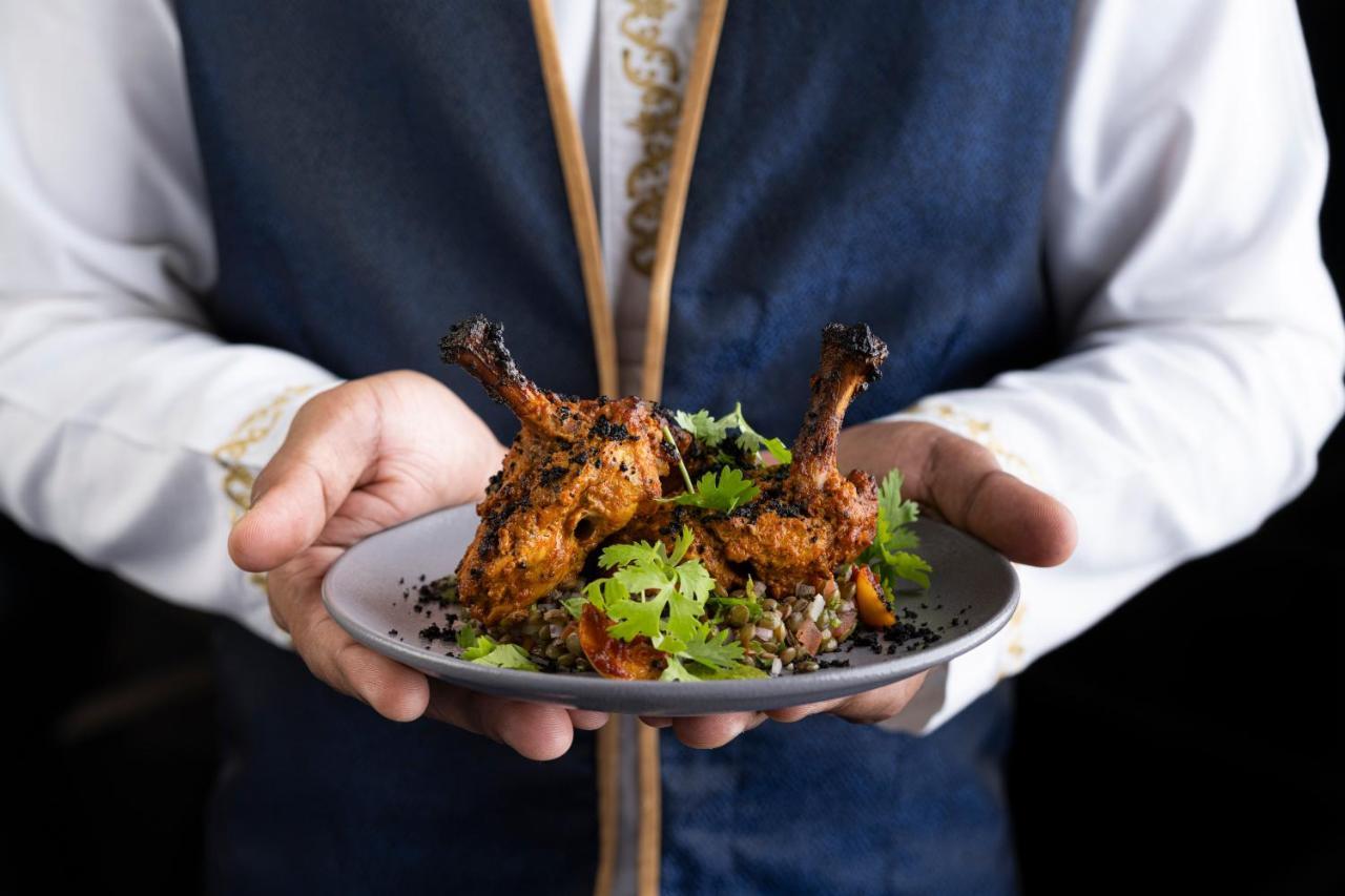 Shangri-La Al Husn, Muscat - Adults Only Resort Esterno foto A waiter holding a plate of food